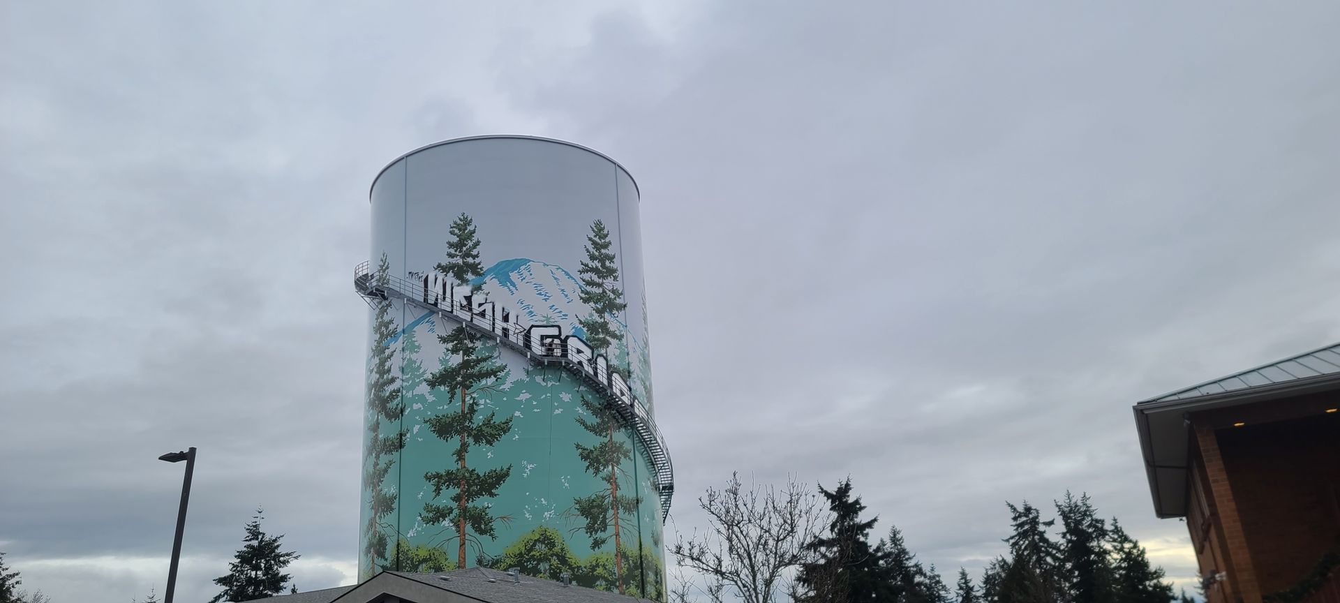 Water tower with a mural of trees and the word 