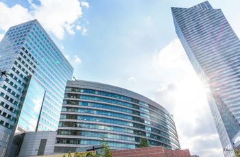 A group of tall buildings against a blue sky with clouds.