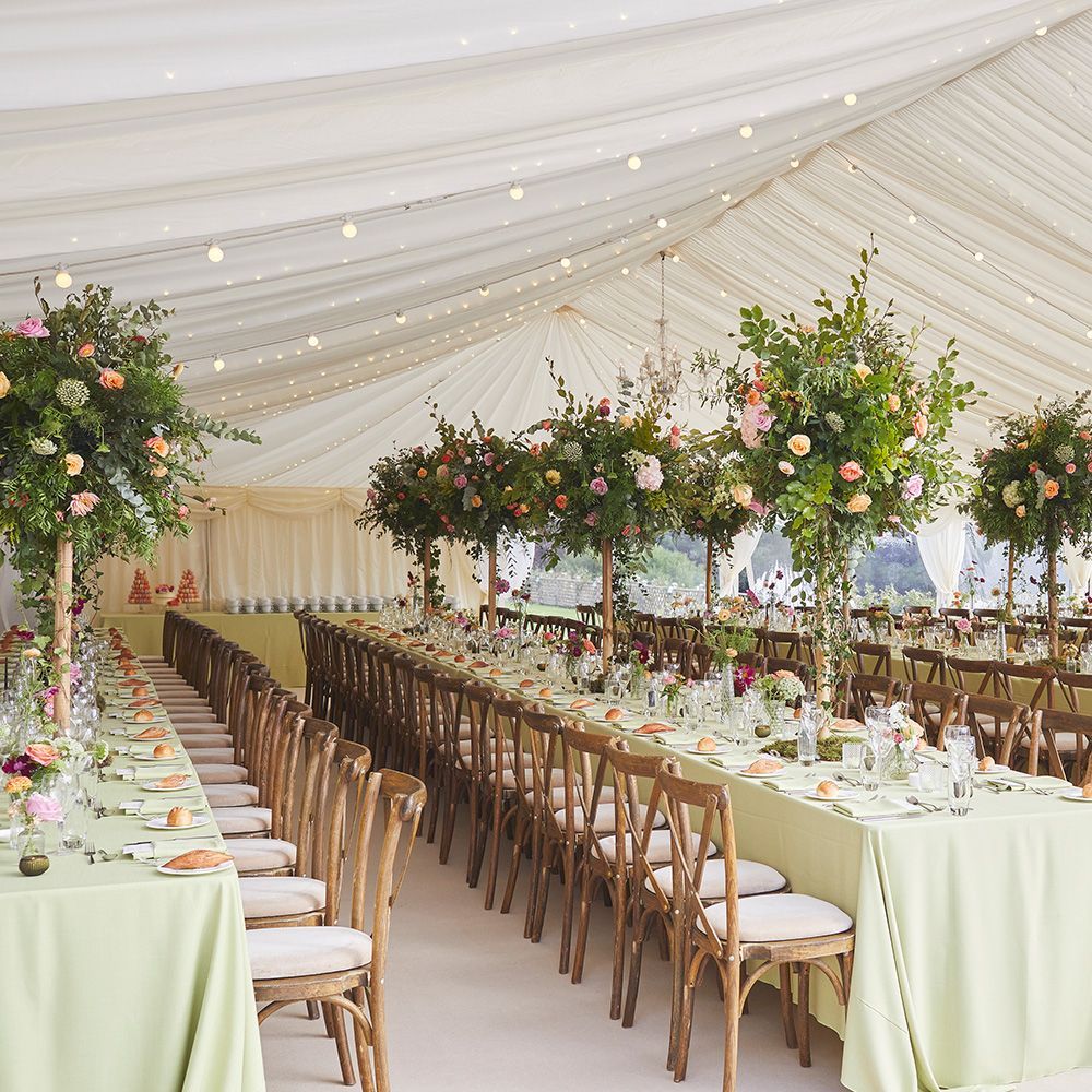 A tent with tables and chairs set up for a wedding reception
