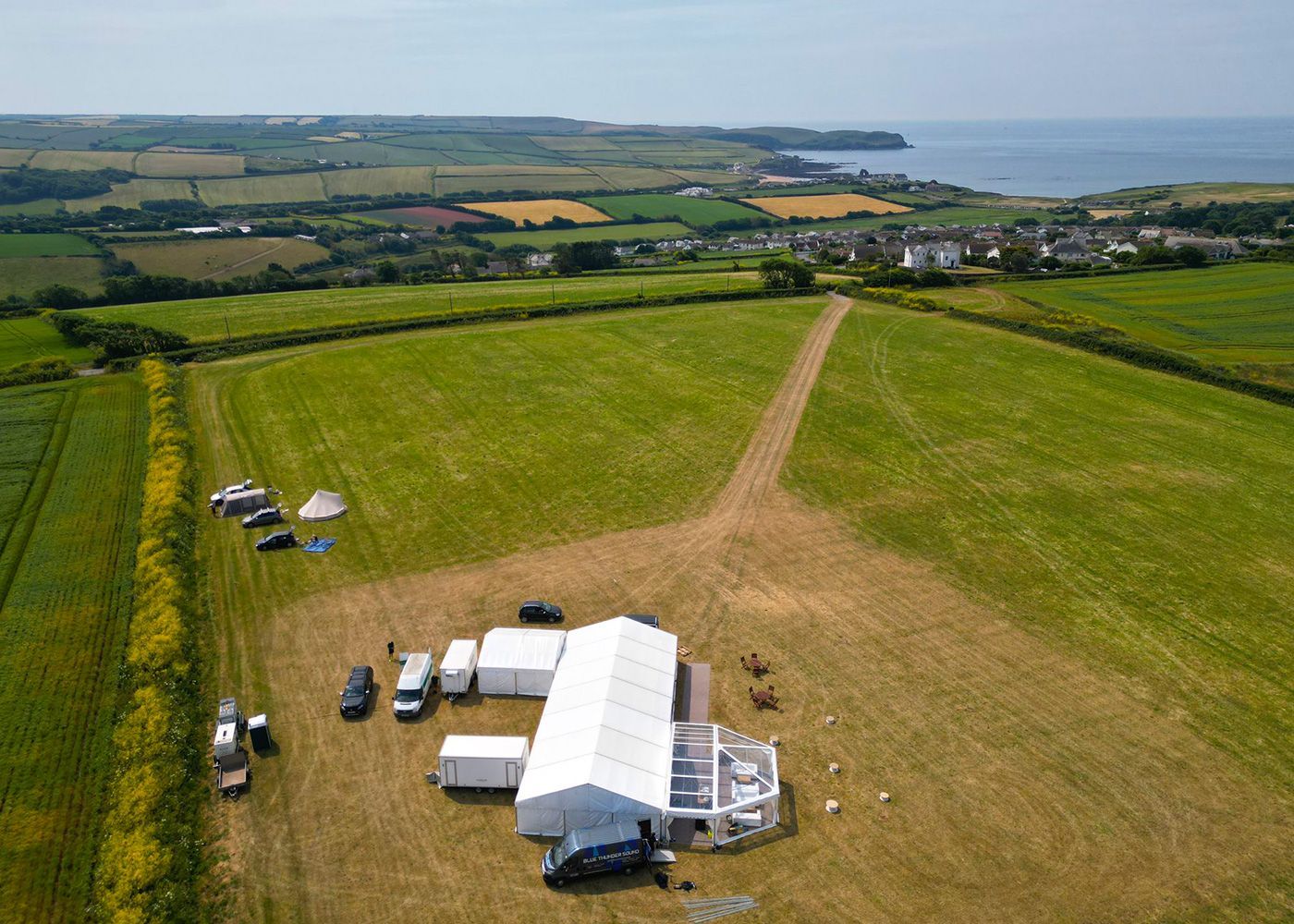 An aerial view of a large field with a white tent in the middle of it.