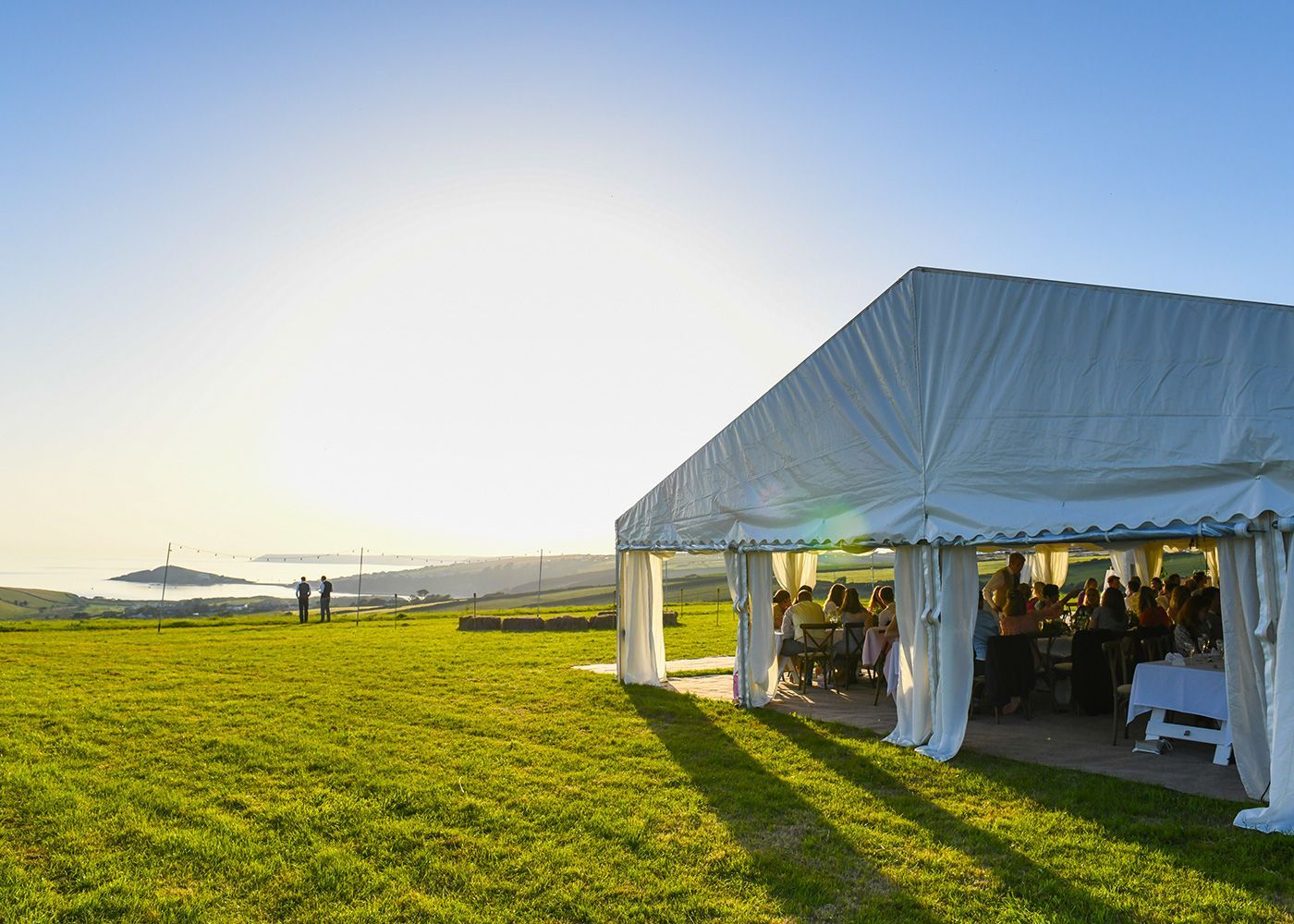 A large white tent is sitting in the middle of a grassy field.
