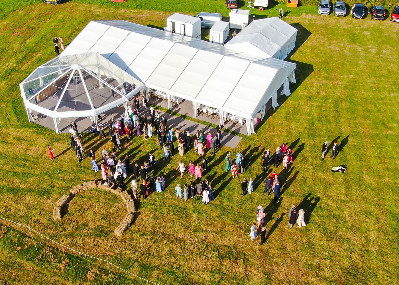 An aerial view of a large tent filled with people in a field.
