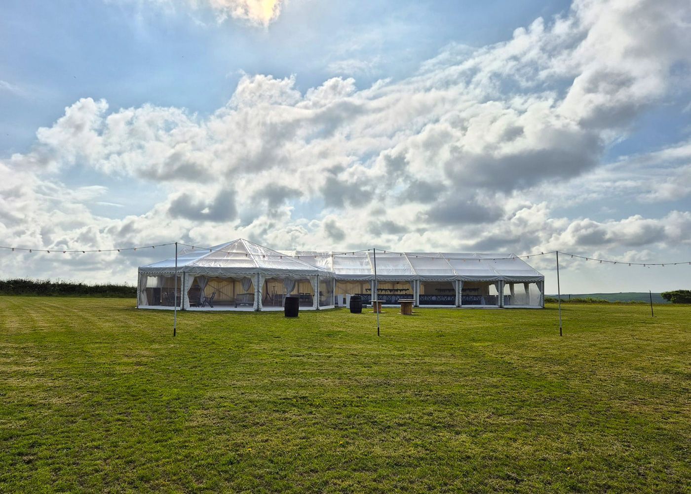 A large white tent is sitting in the middle of a grassy field.