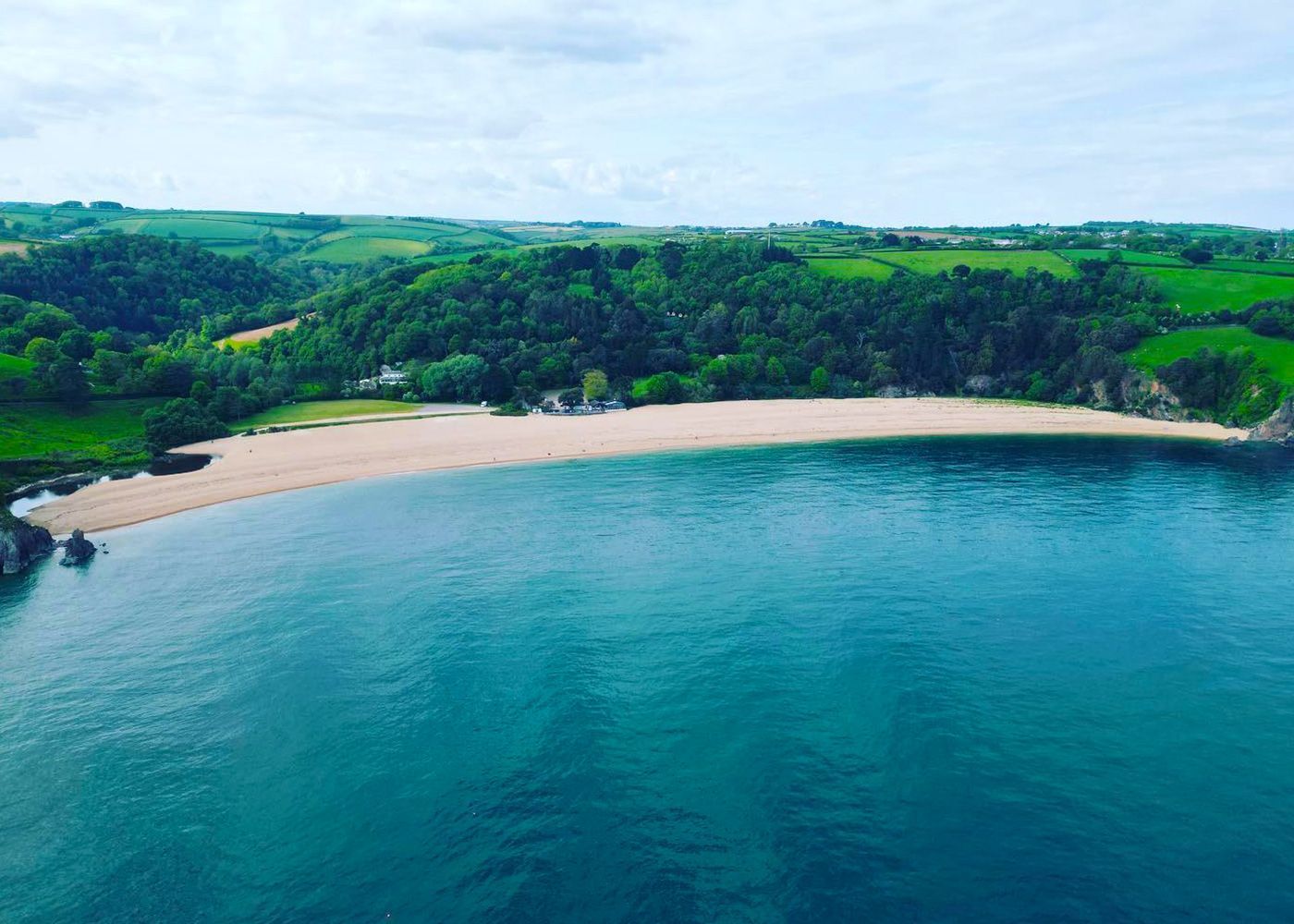 An aerial view of a small beach in the middle of a large body of water surrounded by trees.