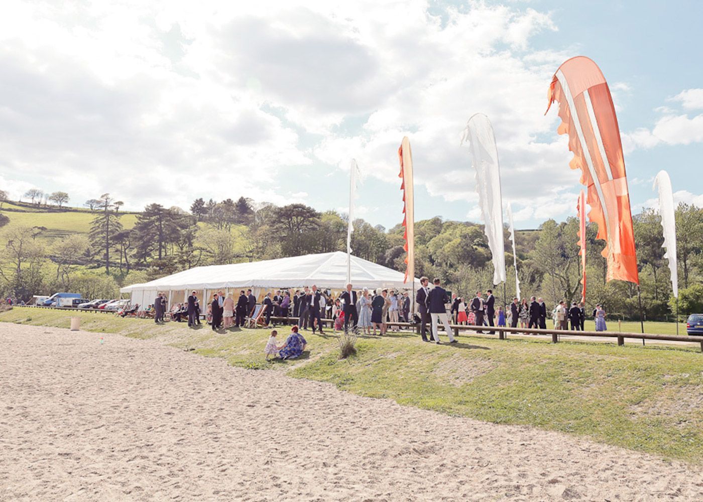 A group of people are standing in front of a tent in a field.