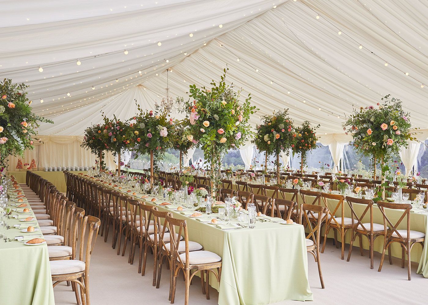 A large tent with tables and chairs set up for a wedding reception.