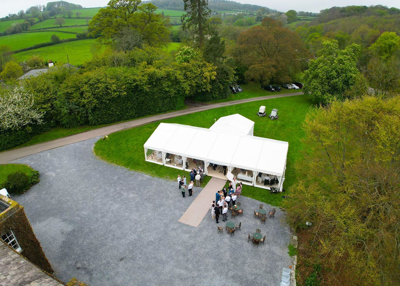 An aerial view of a large white tent in a grassy field.