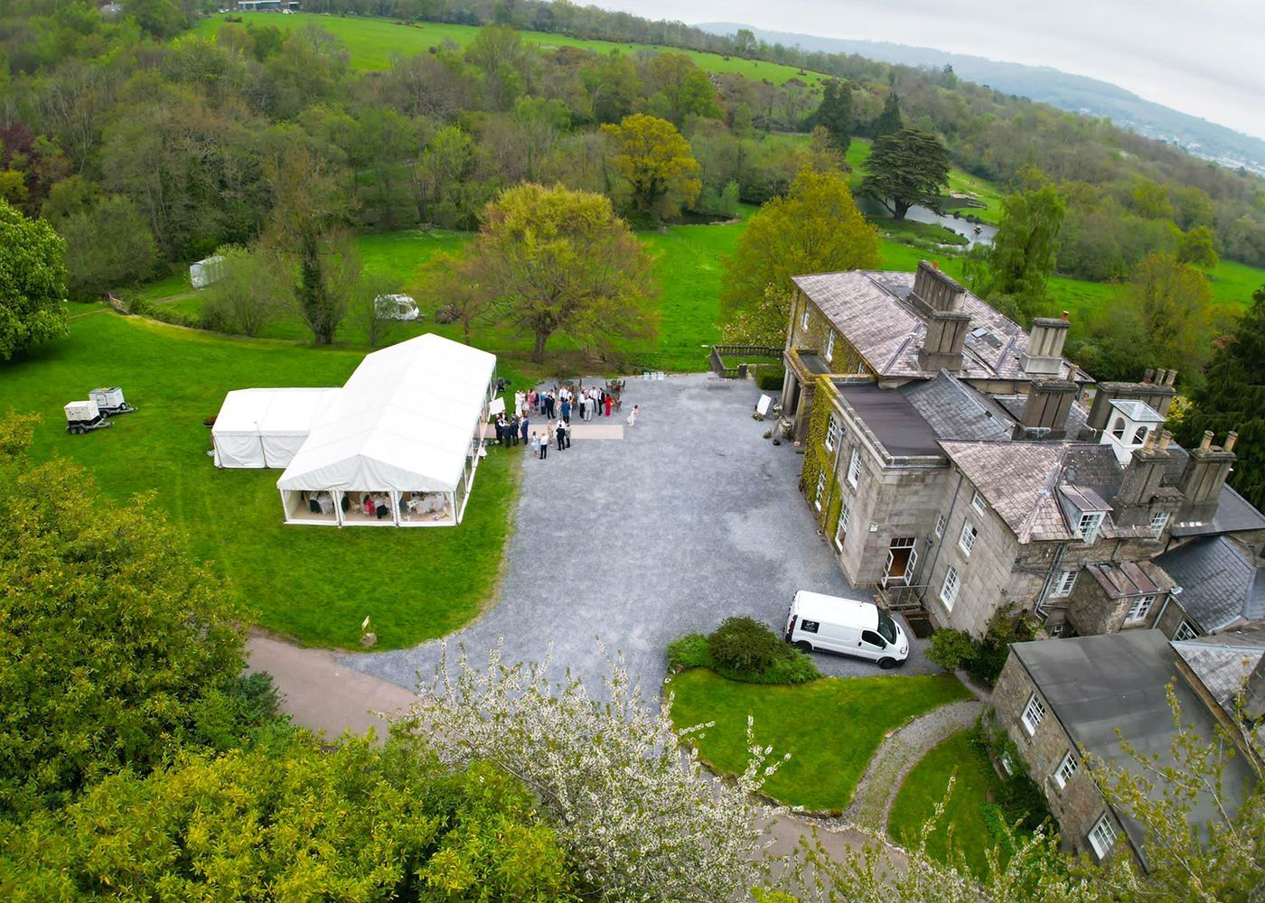 An aerial view of a large house surrounded by trees and grass.