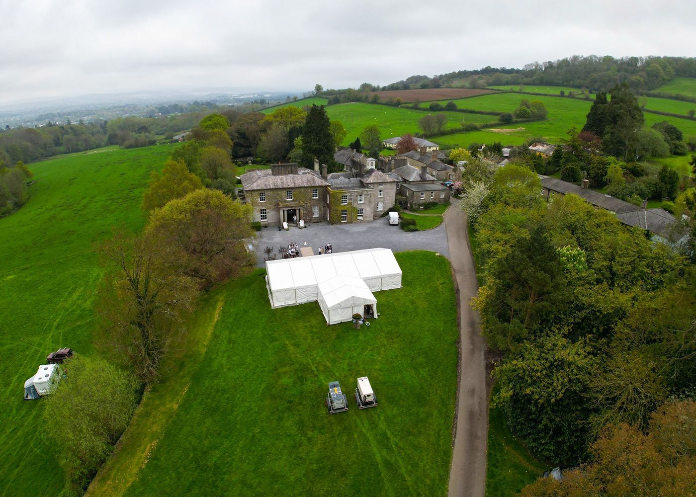 An aerial view of a large grassy field with a white tent in the middle.