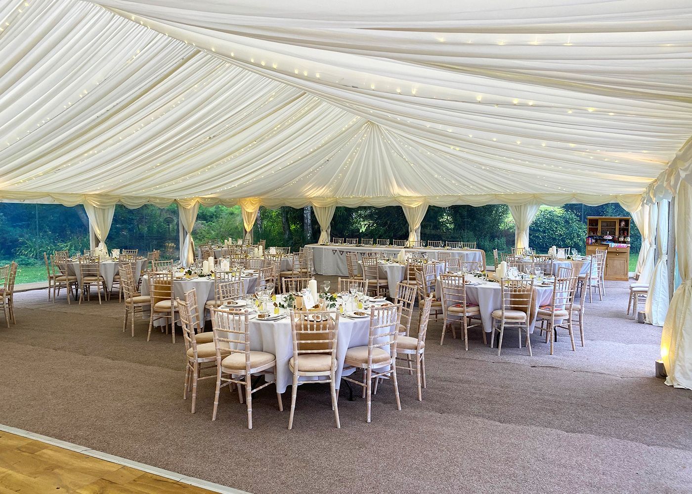 A large tent with tables and chairs set up for a wedding reception.