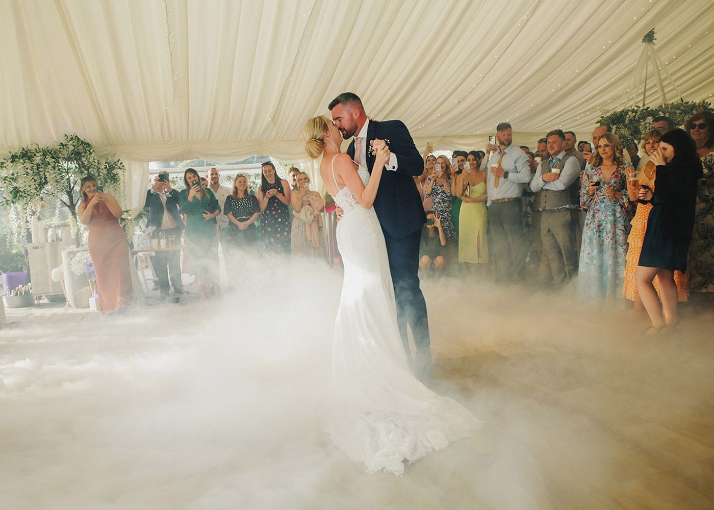 A bride and groom are dancing in a tent surrounded by smoke.
