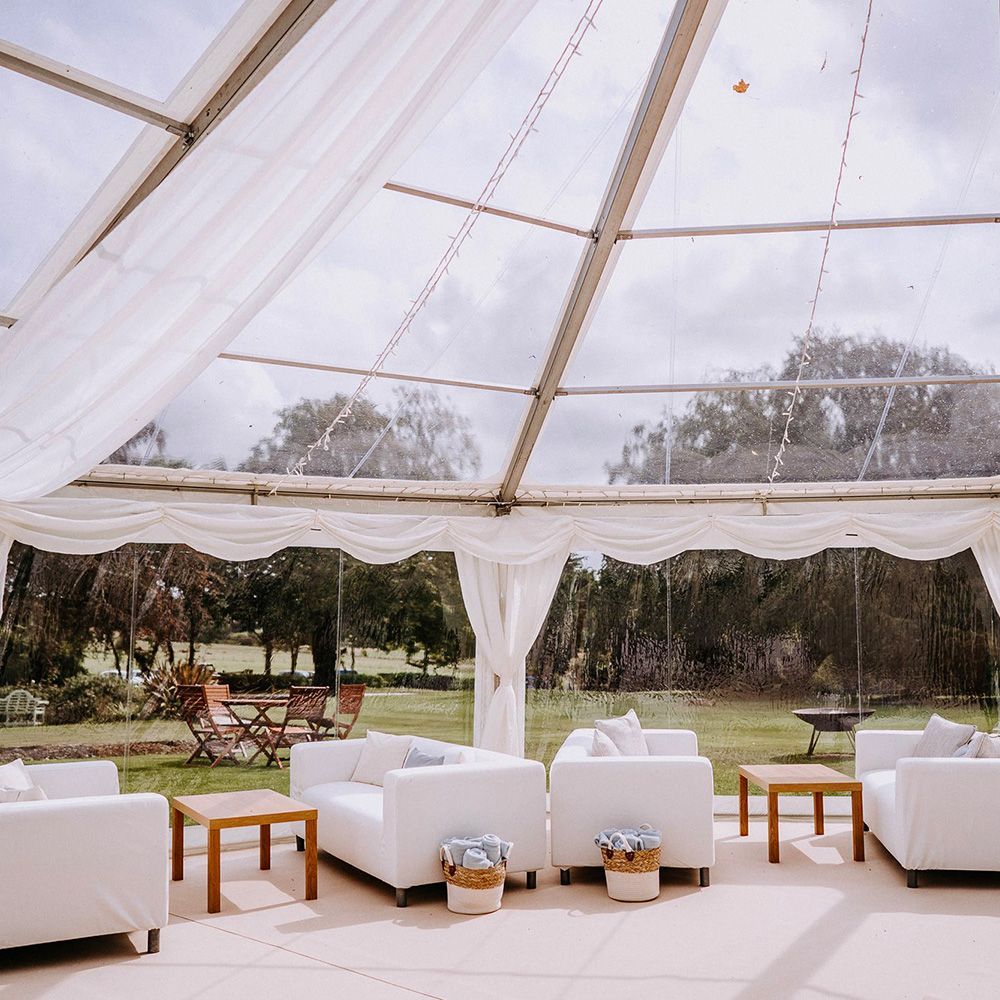 A clear tent with white furniture inside of it