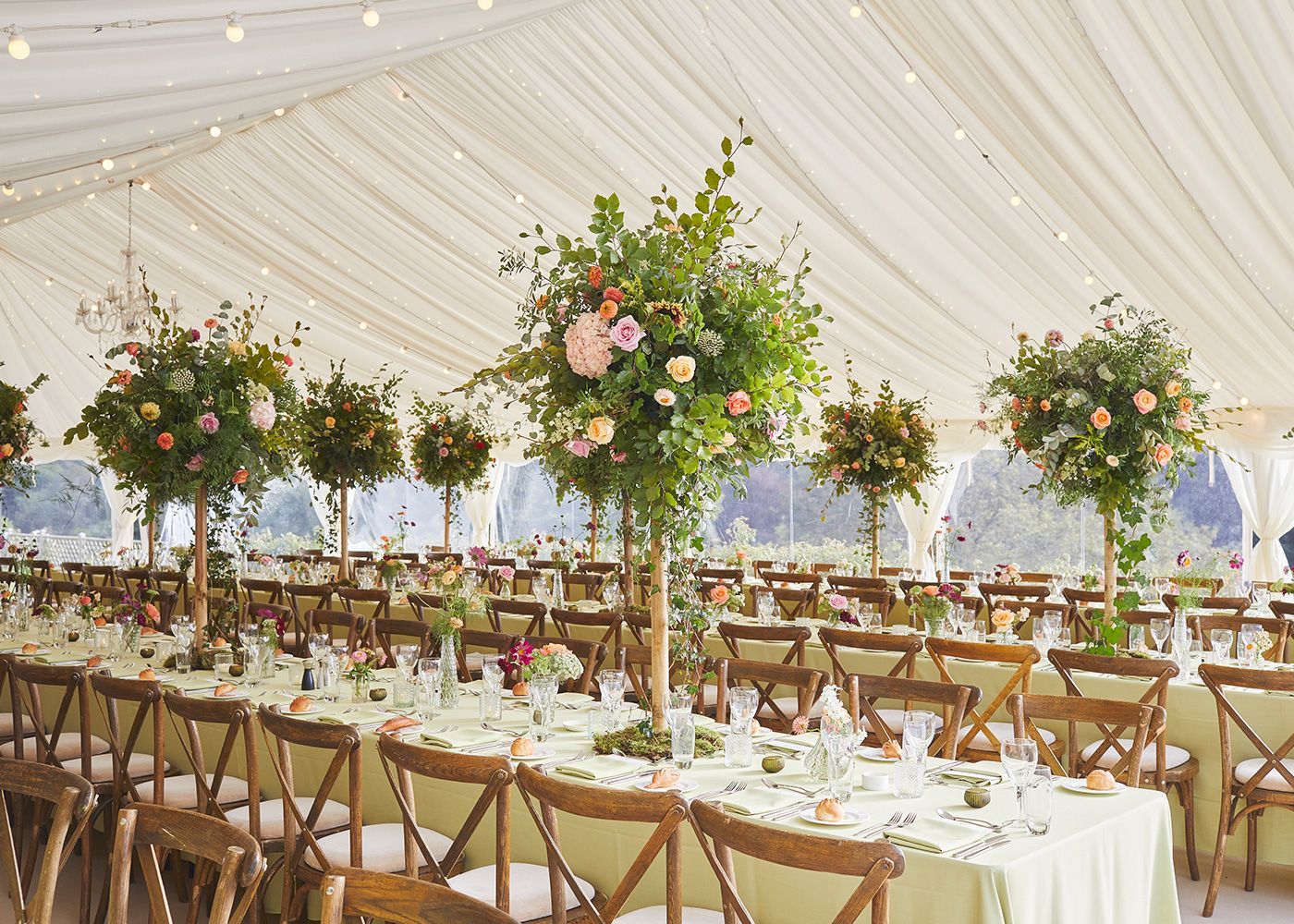 A large tent with tables and chairs set up for a wedding reception.