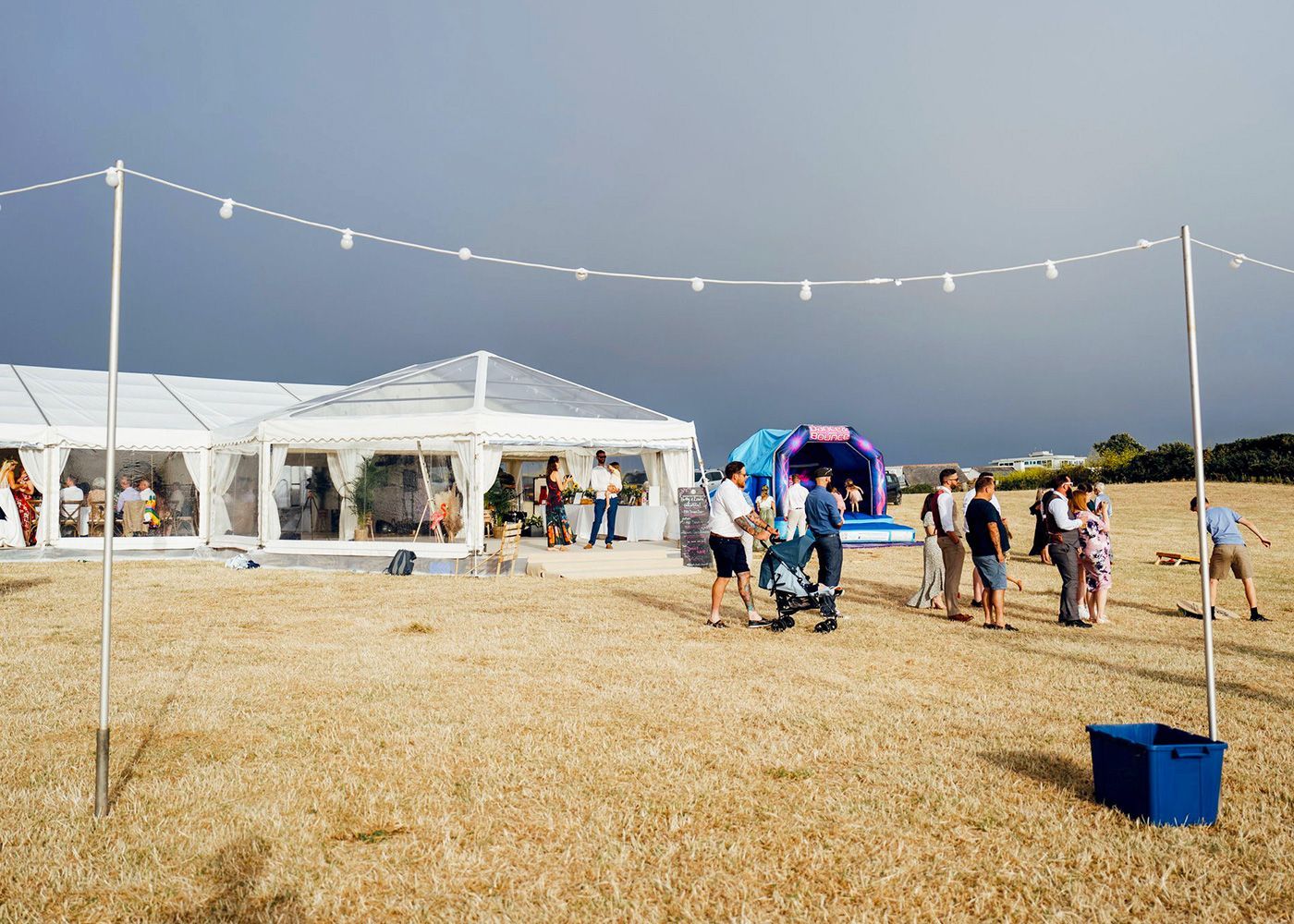 A group of people are standing in a field in front of a tent.
