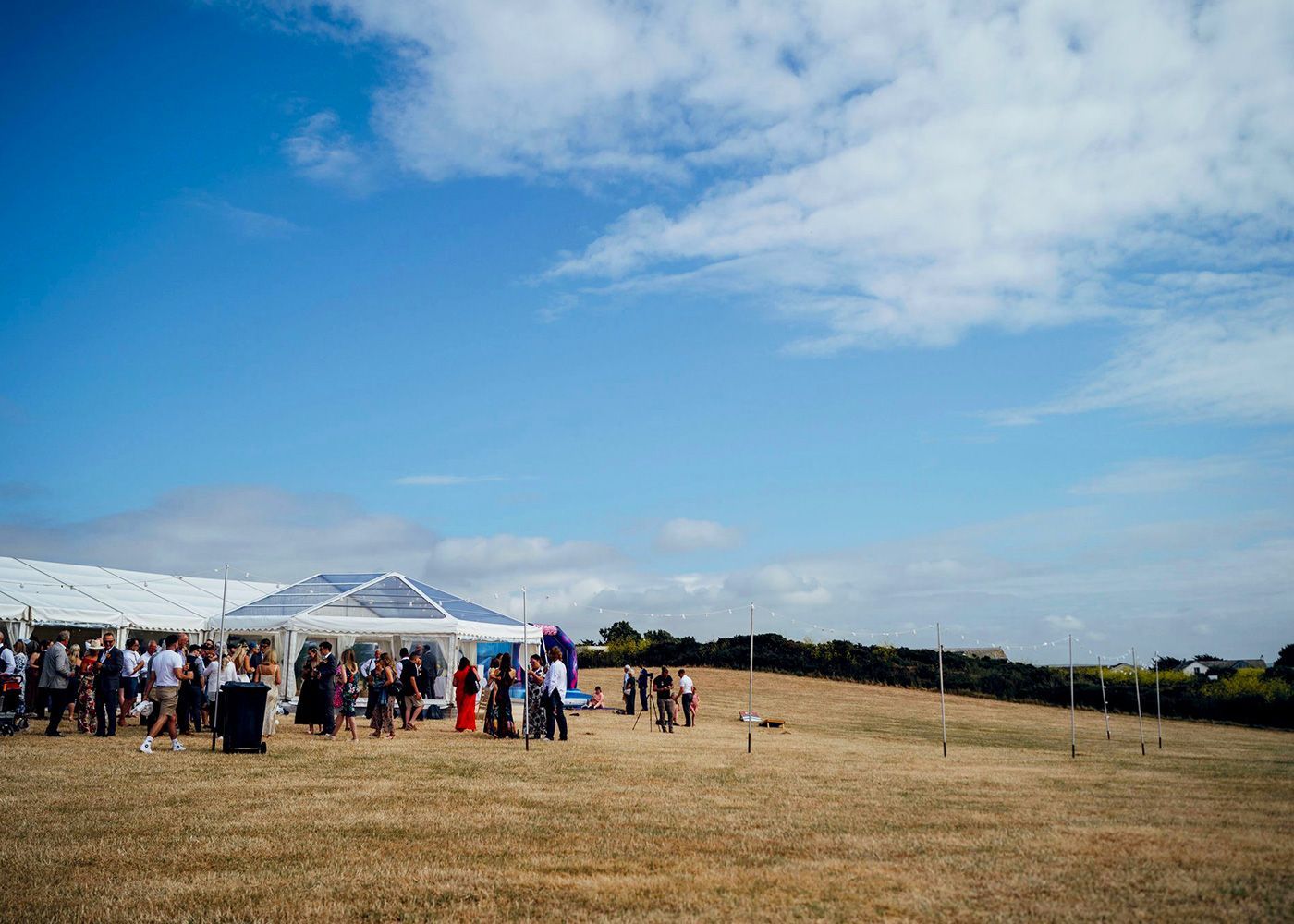 A group of people are standing in a field in front of a tent.