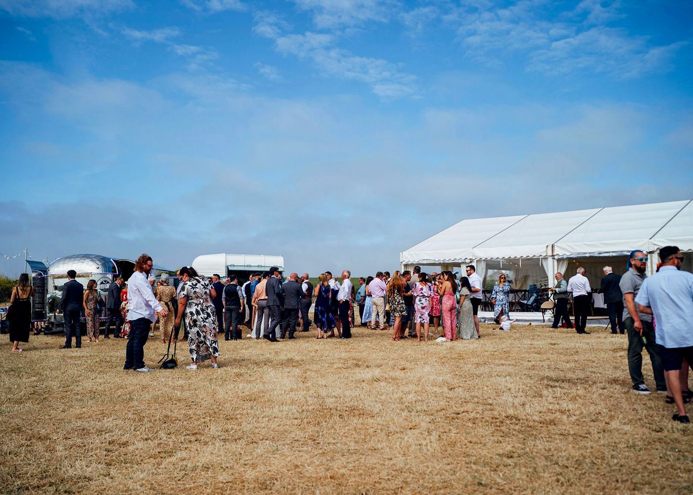 A group of people are standing in a field in front of a tent.