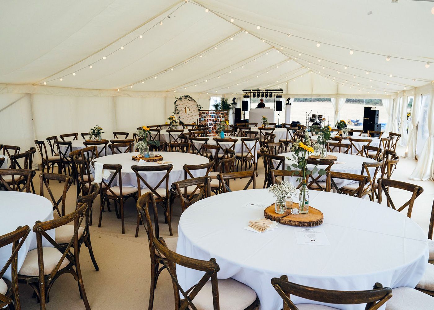 A large tent with tables and chairs set up for a wedding reception.