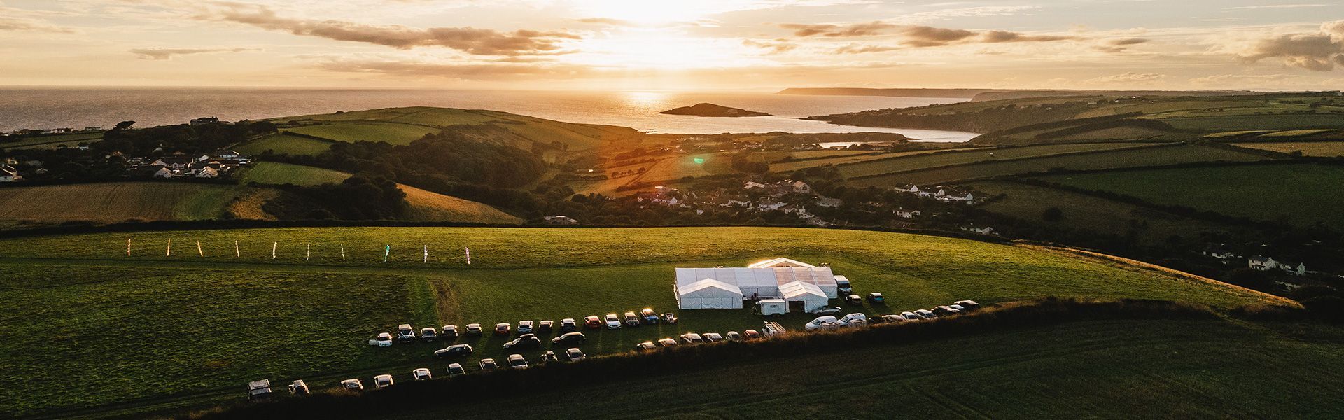 An aerial view of a house in the middle of a field at sunset.