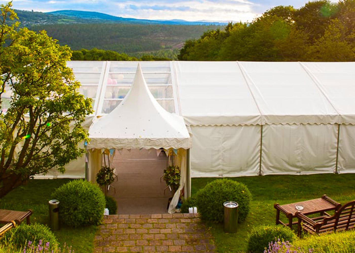 A large white tent is sitting in the middle of a lush green field.