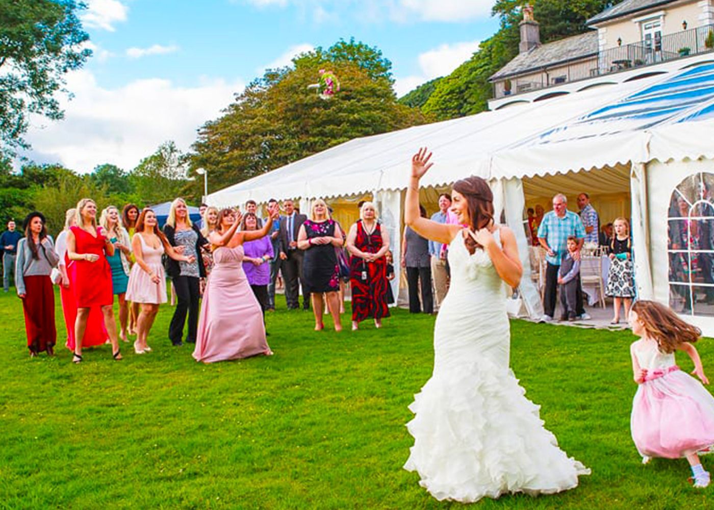 A bride is throwing a bouquet of flowers to her wedding guests.