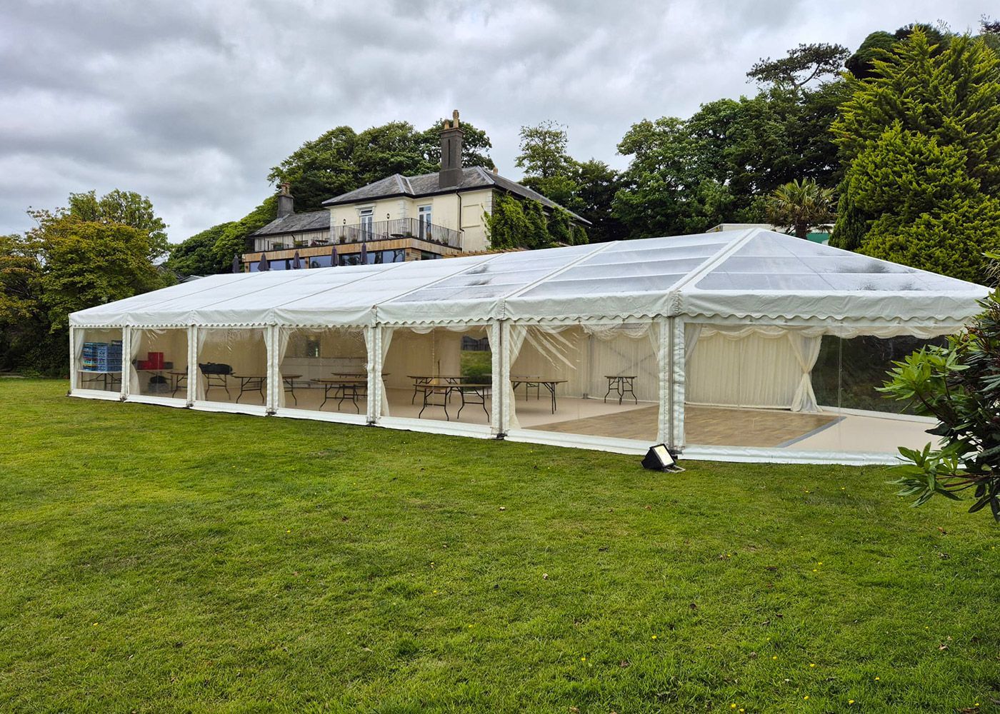 A large white tent is sitting in the middle of a grassy field.