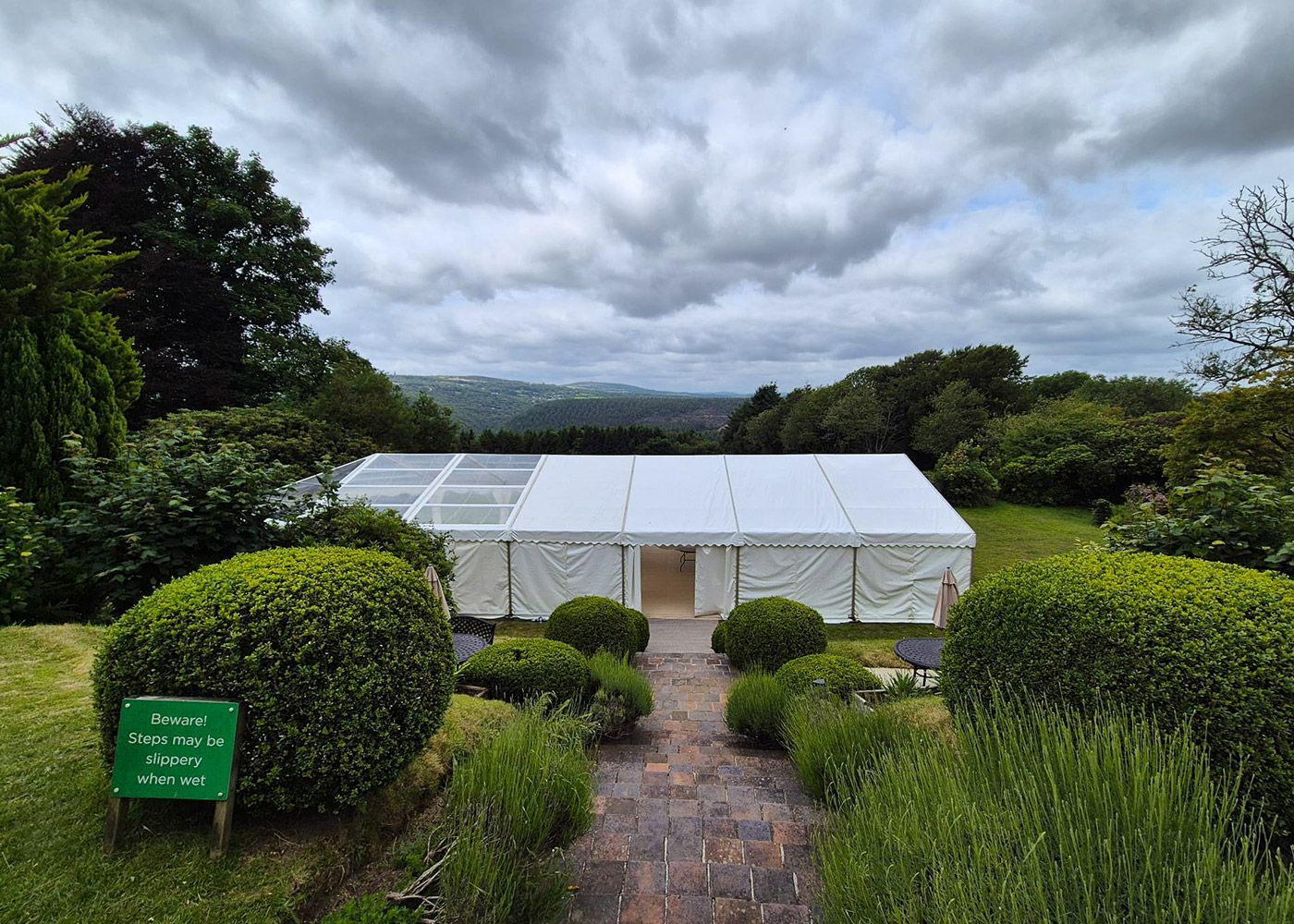 A large white tent is sitting in the middle of a lush green field.