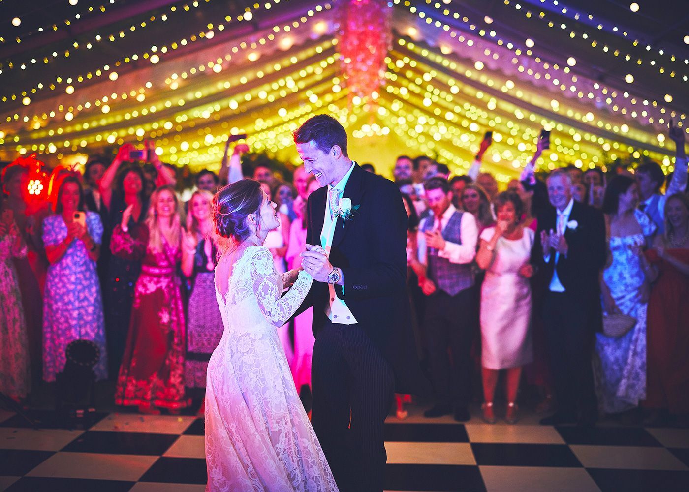 A bride and groom are dancing in front of a crowd at their wedding reception.