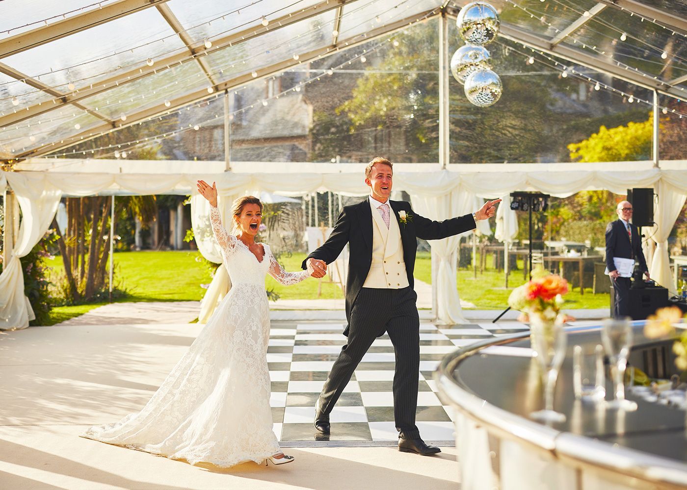 A bride and groom are dancing in a clear tent.