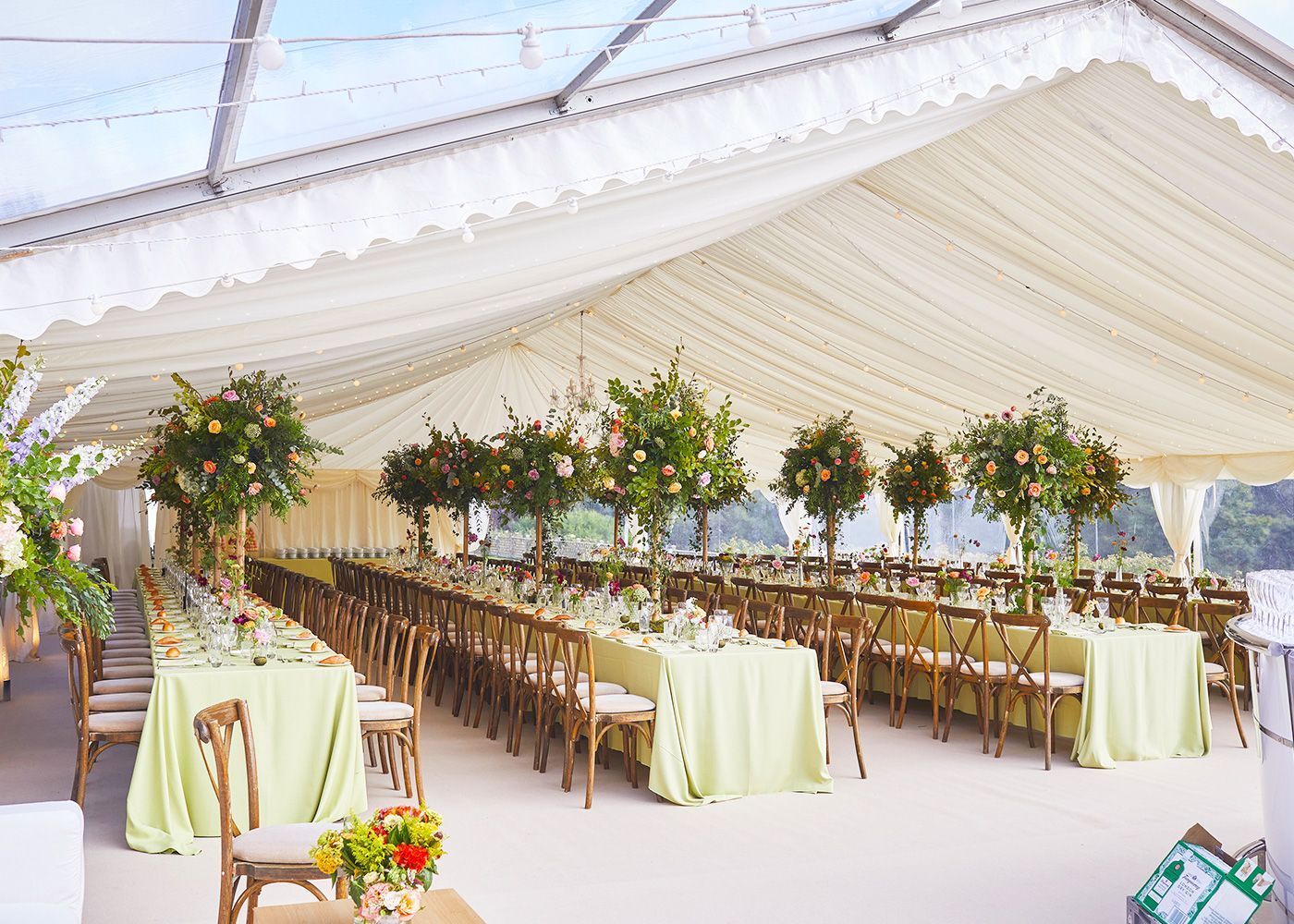 A large tent with tables and chairs set up for a wedding reception.