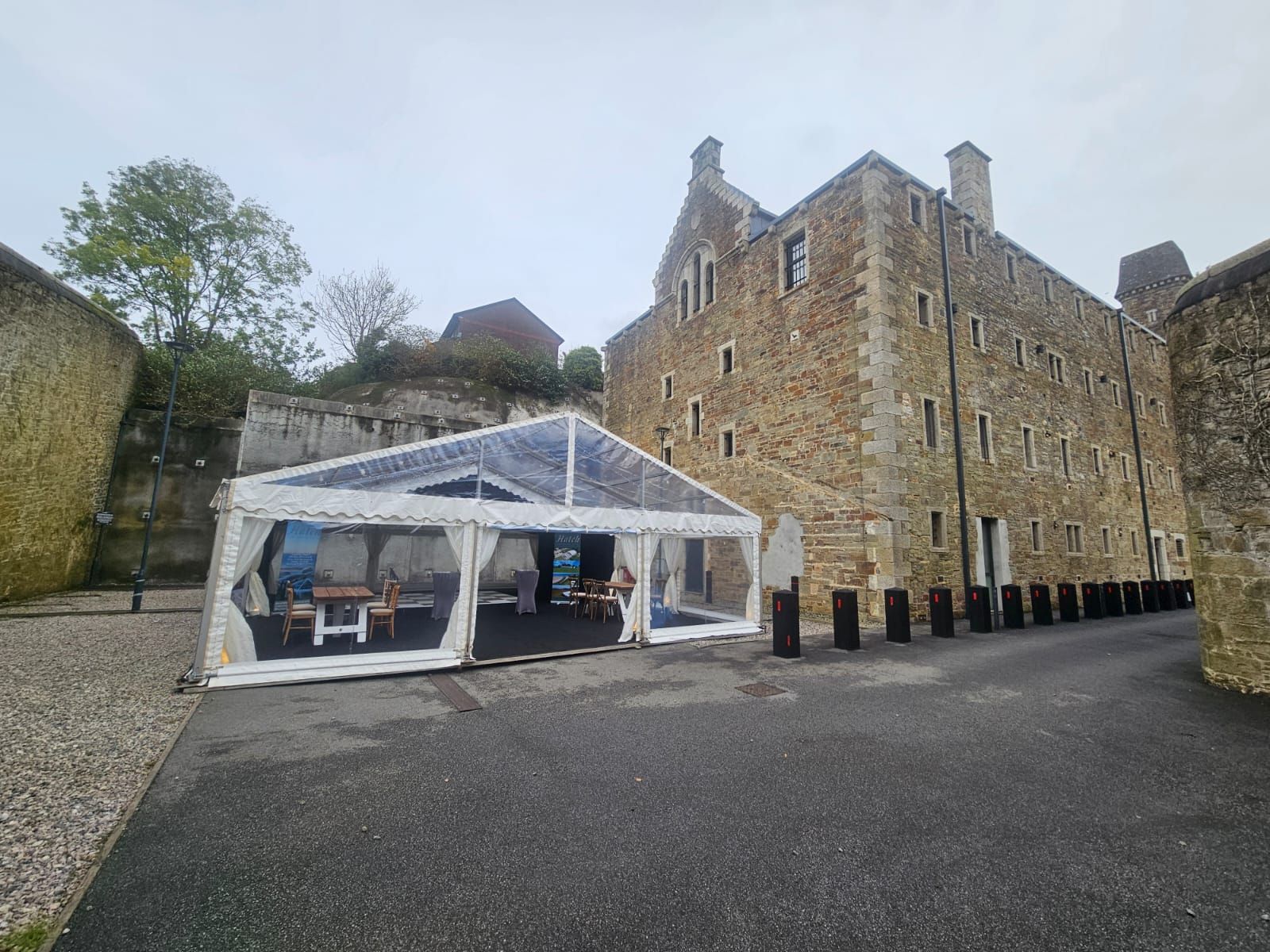 A clear tent is sitting in front of a large stone building.