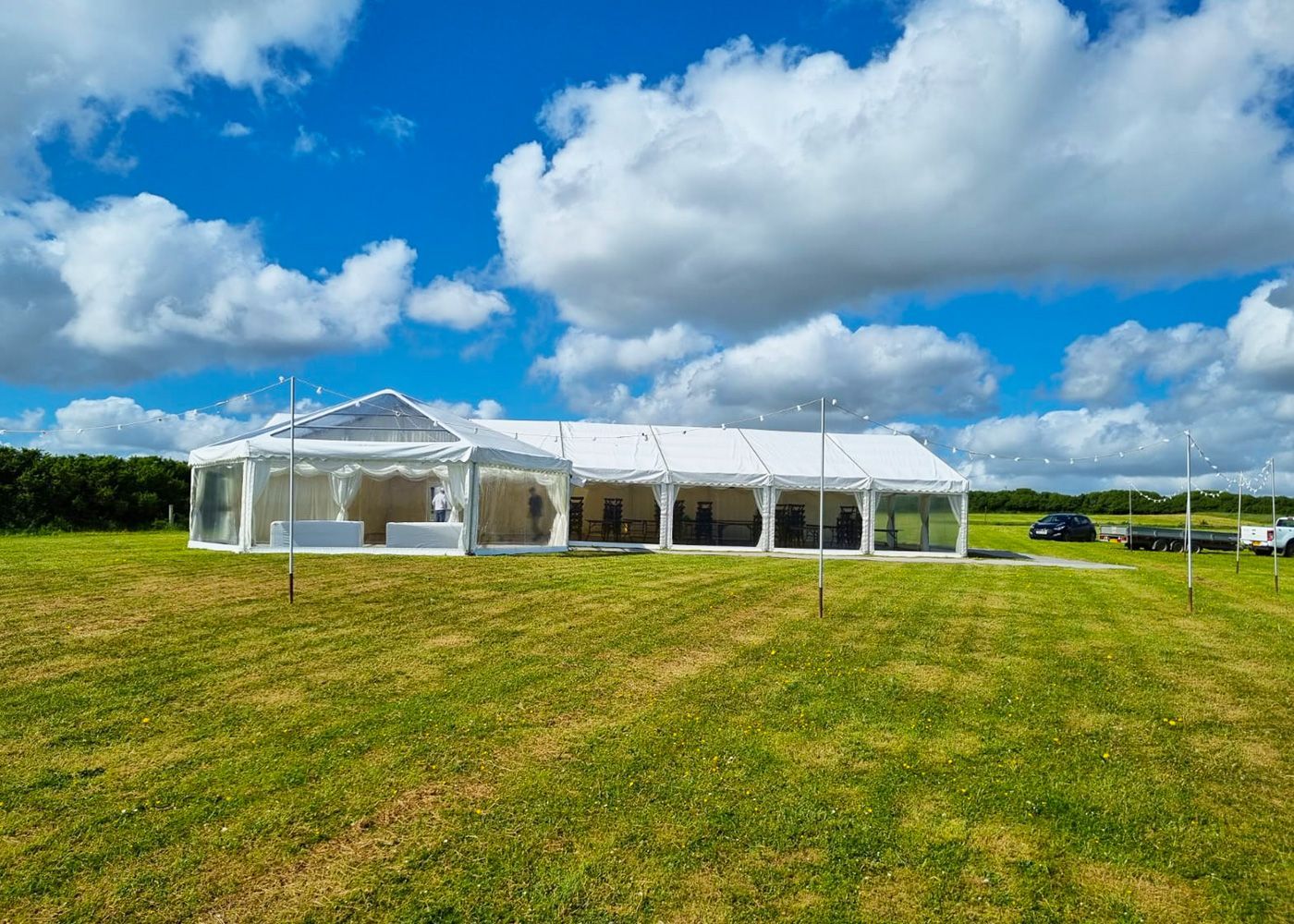 A large white tent is sitting in the middle of a grassy field.