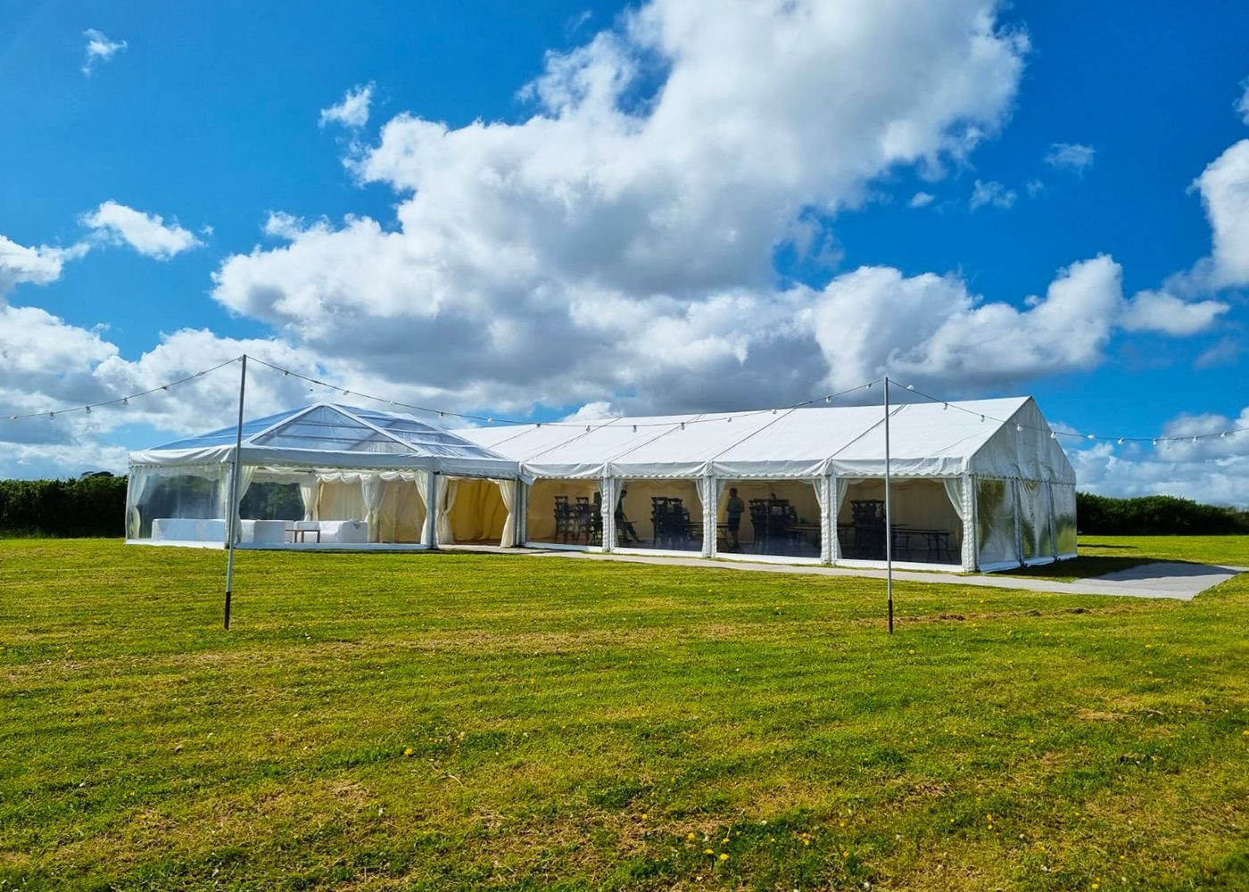 A large white tent is sitting in the middle of a grassy field.