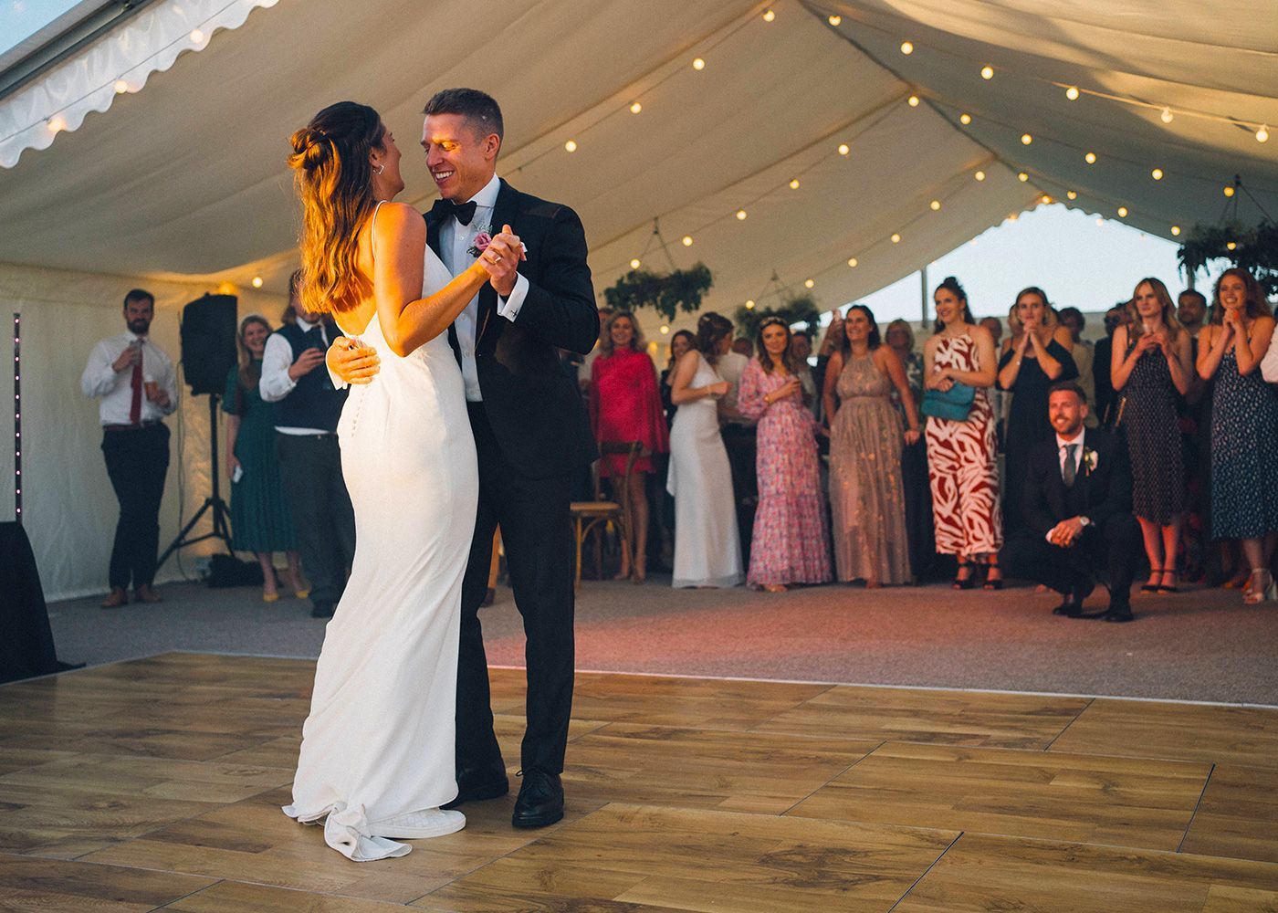A bride and groom are dancing under a tent at their wedding reception.