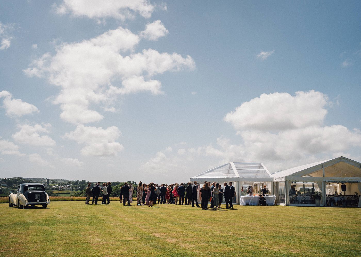 A group of people are standing in a field in front of a tent.
