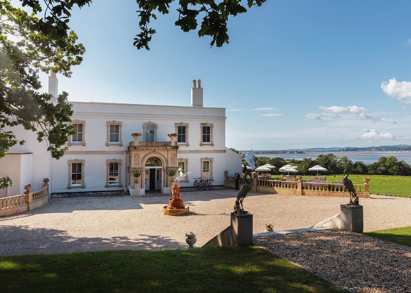 A large white house with a gravel driveway in front of it