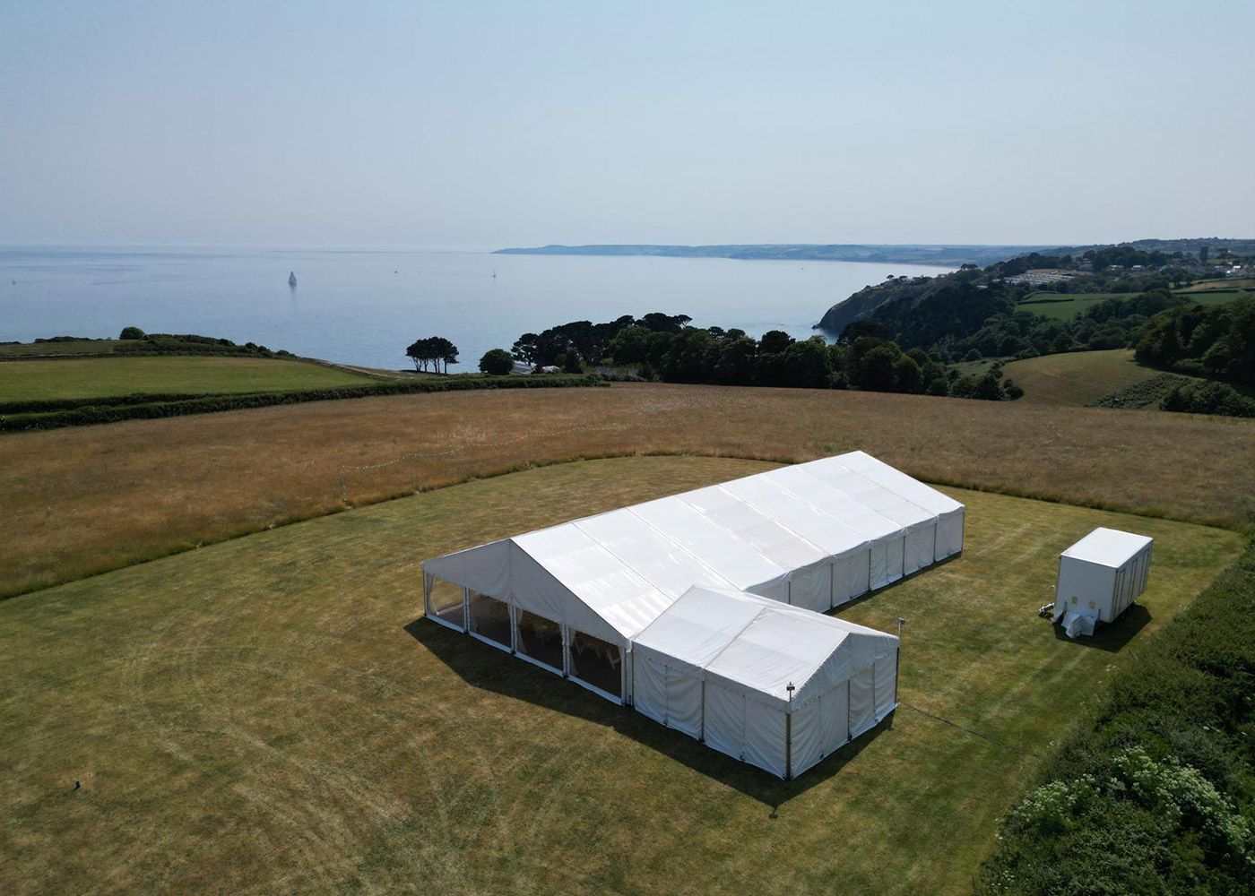 An aerial view of a large white tent in a field.