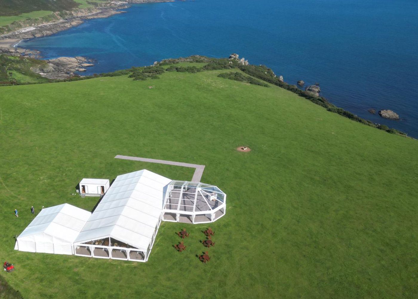 An aerial view of a large white tent in a grassy field