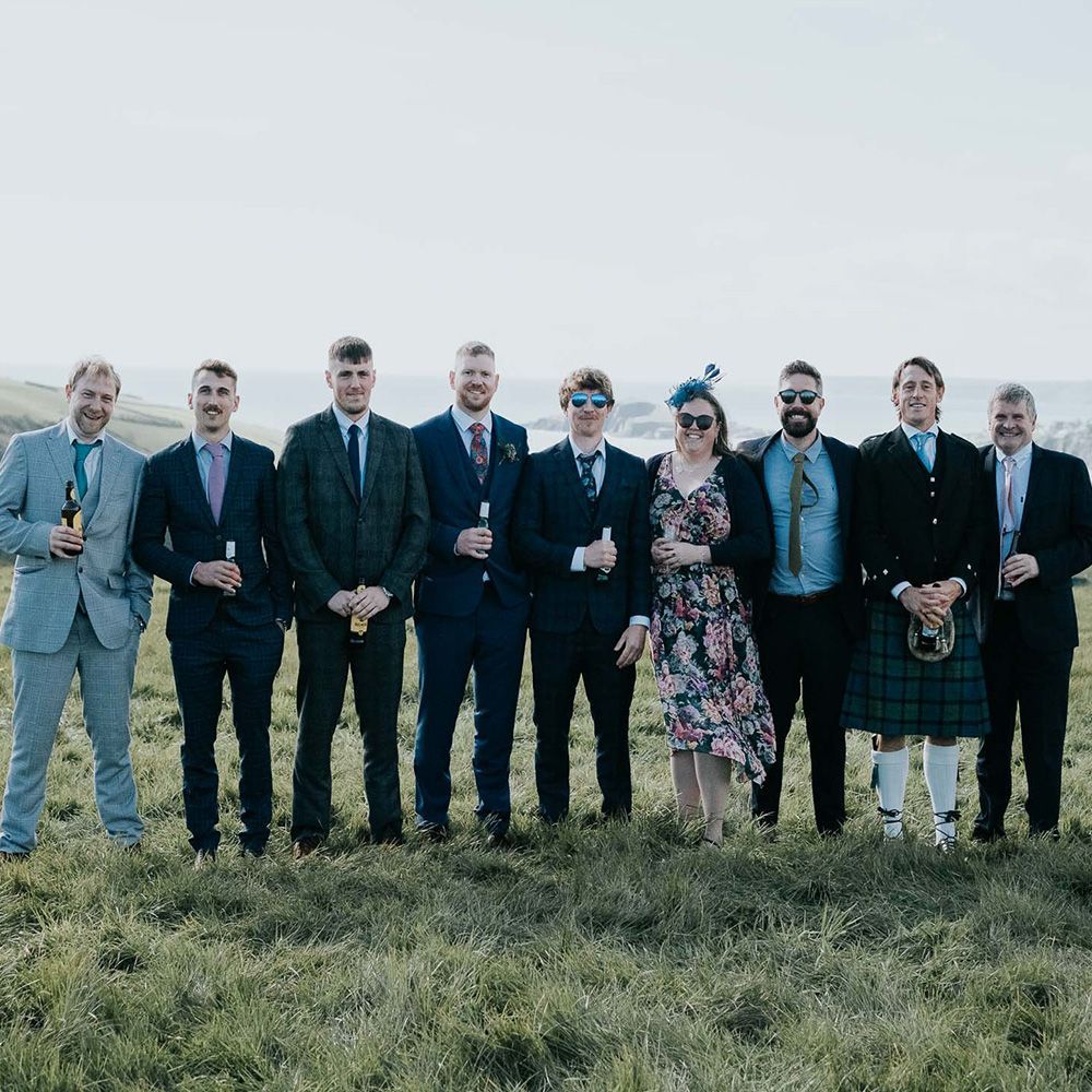 A group of people in suits and ties are standing in a grassy field.