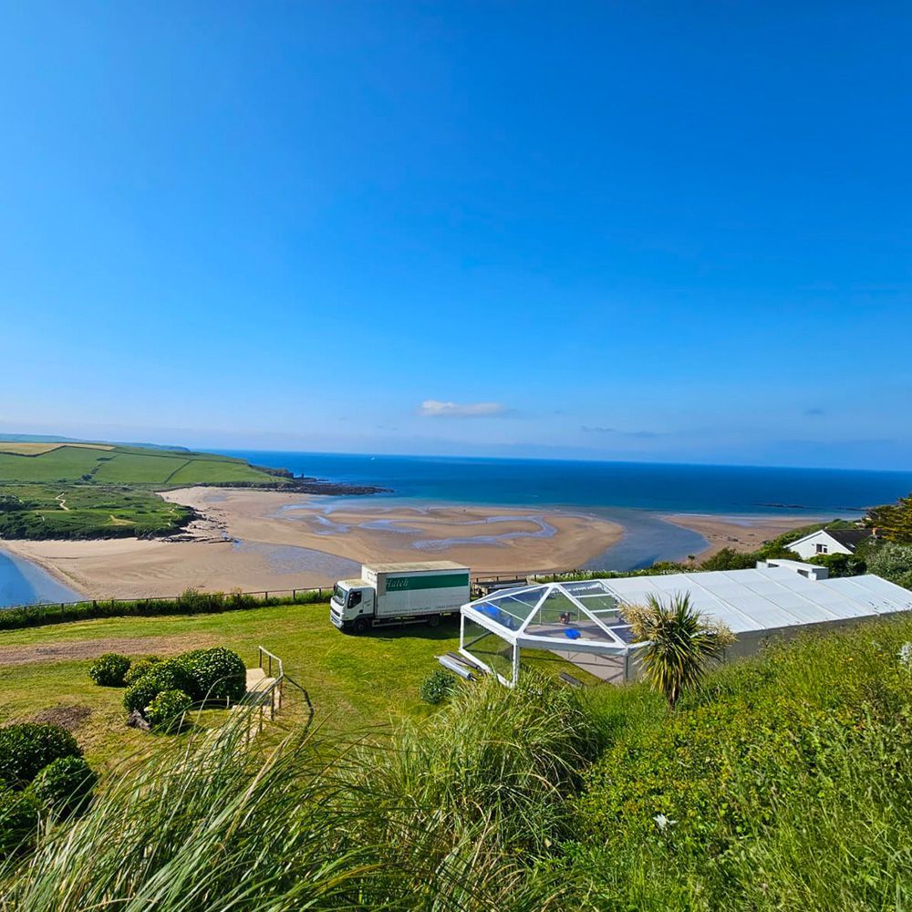A truck is parked on top of a grassy hill overlooking the ocean.