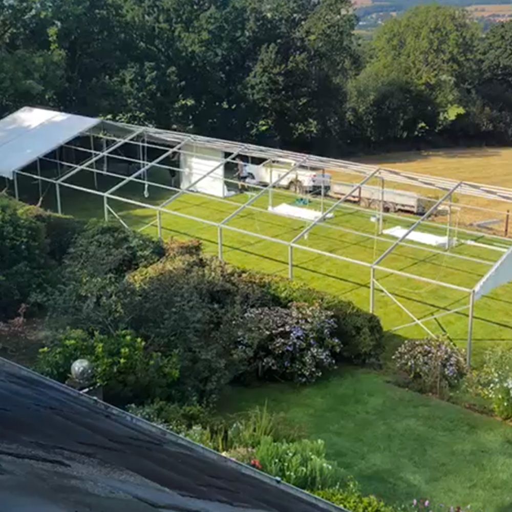 A large white tent is sitting on top of a lush green field.