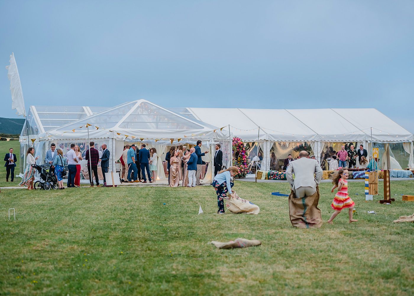 A group of people are standing in a field in front of a tent.