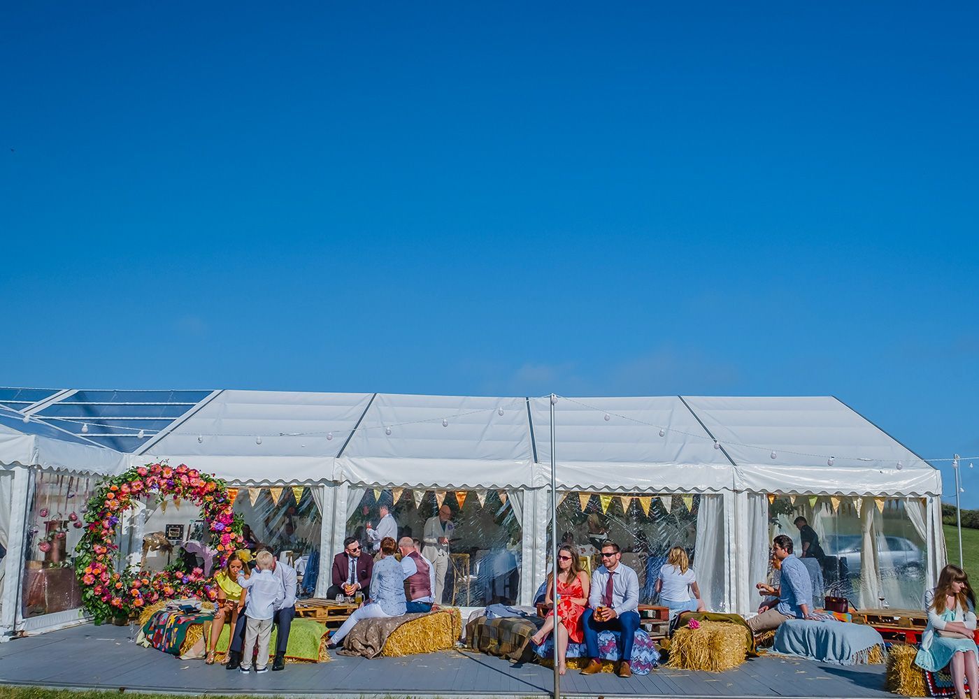 A group of people are standing outside of a large white tent.
