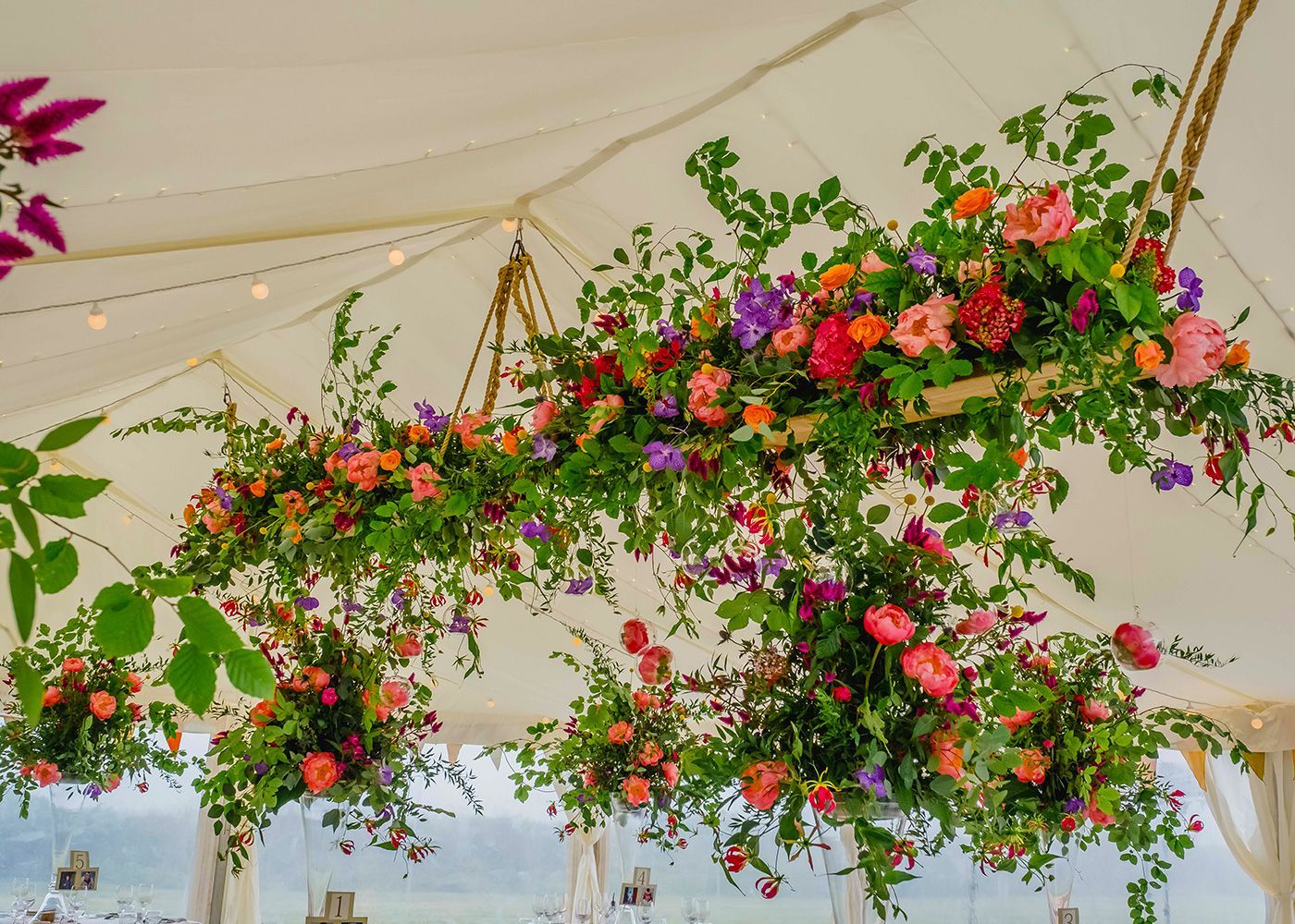 A white tent with flowers hanging from the ceiling.