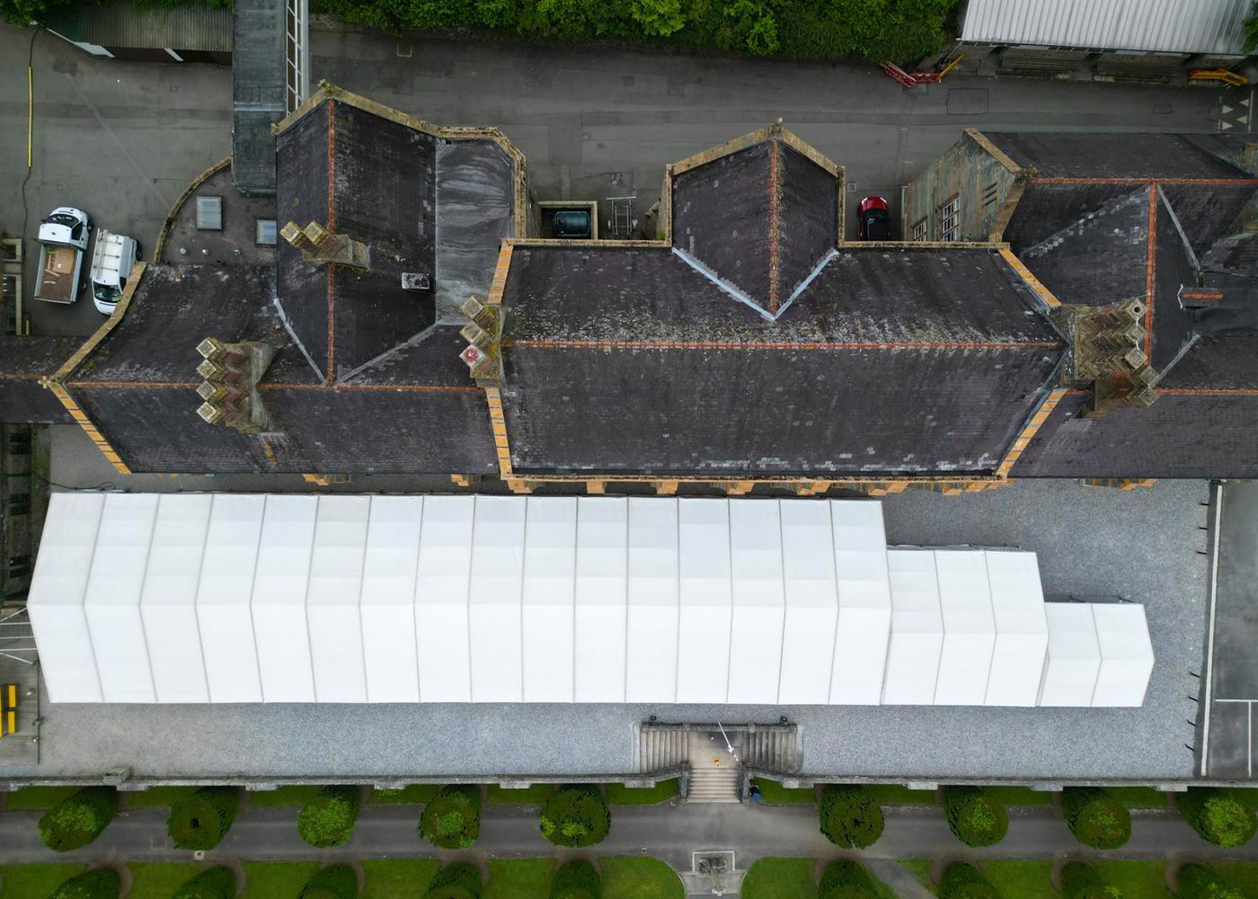 An aerial view of a large building with a white tent on the roof.