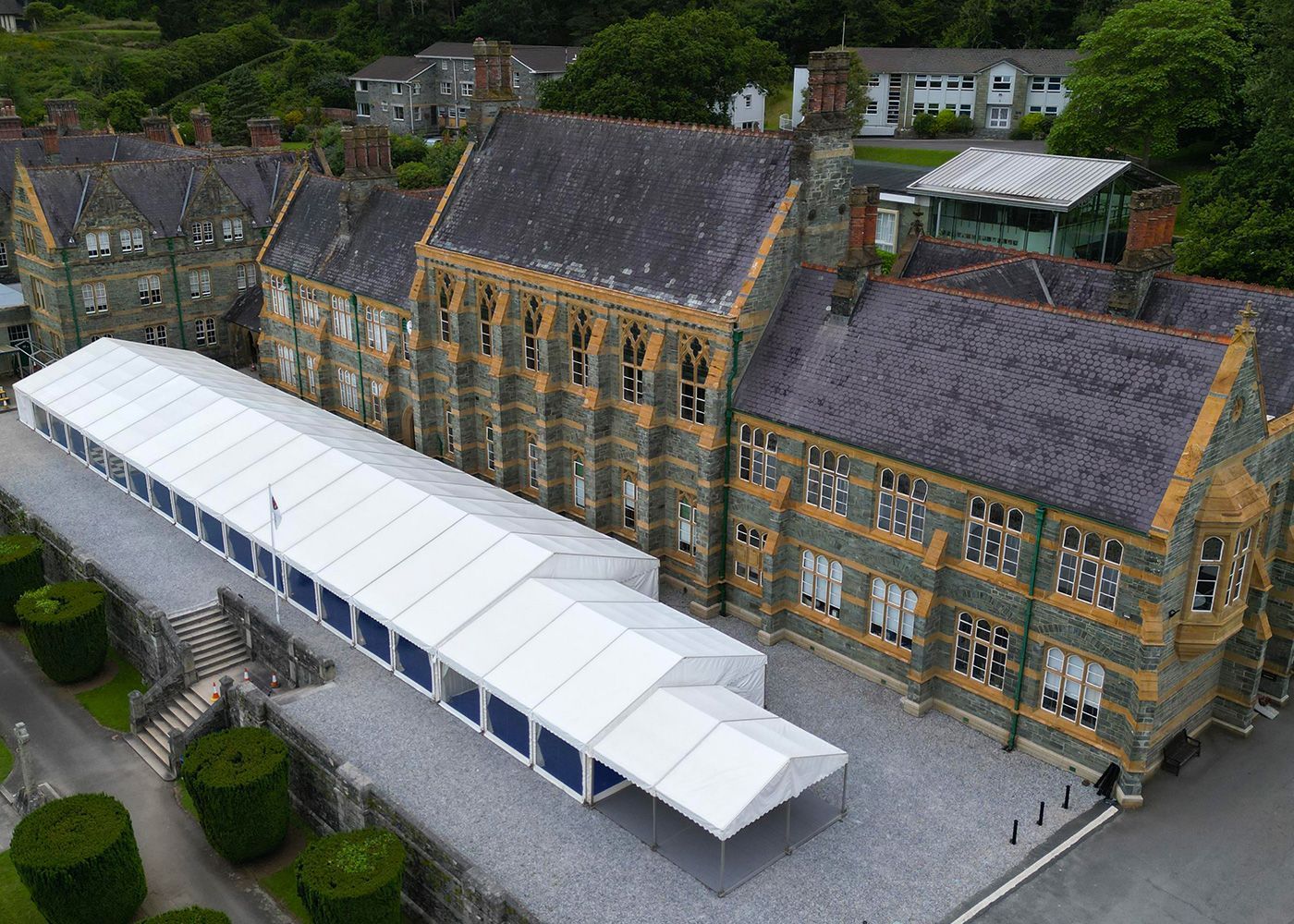 An aerial view of a large building with a white tent in front of it.
