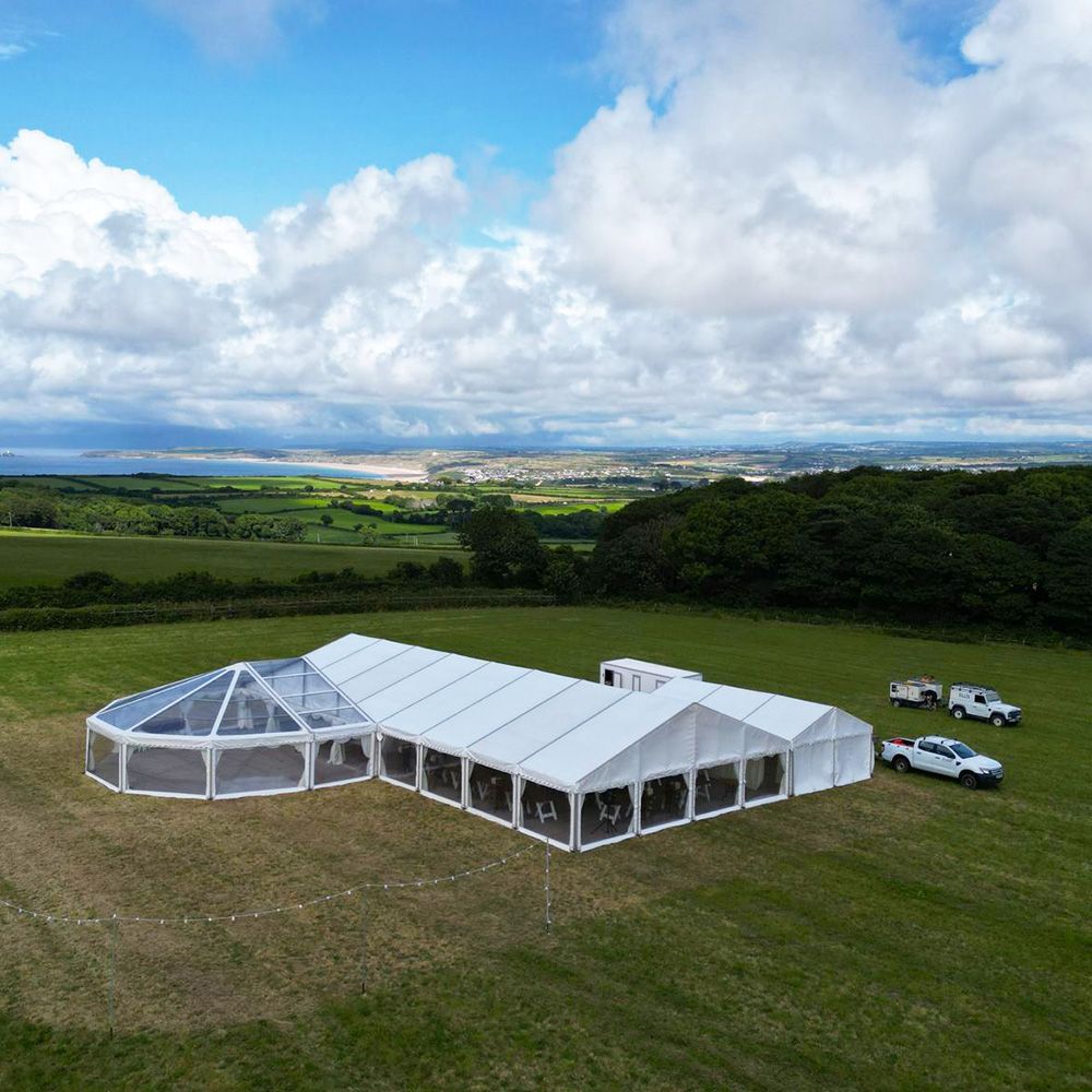 An aerial view of a large white tent in a grassy field.