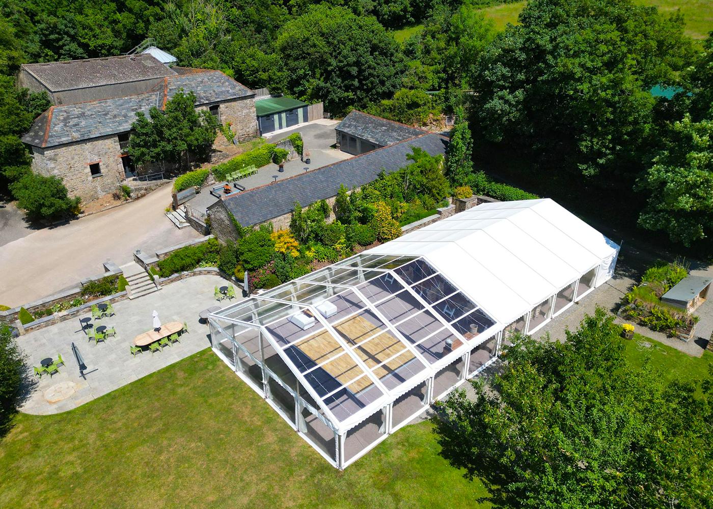 An aerial view of a large clear tent in the middle of a field.