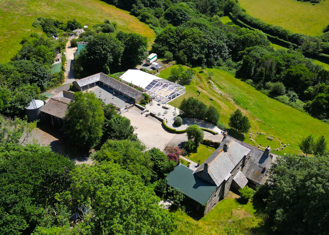 An aerial view of a farm surrounded by trees and grass