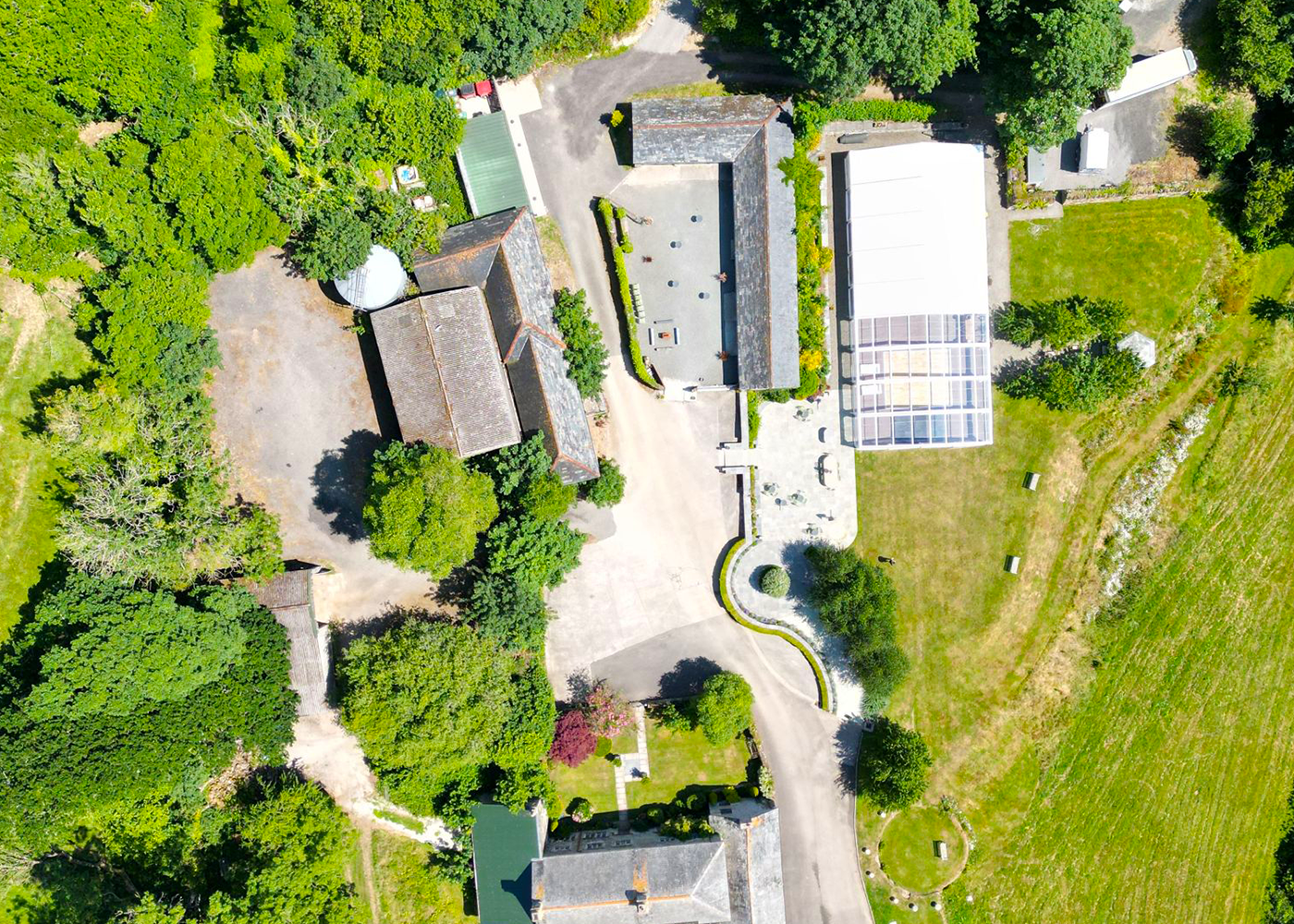 An aerial view of a house surrounded by trees and grass