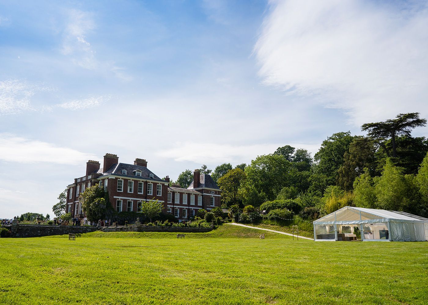 There is a large house in the background and a tent in the foreground.